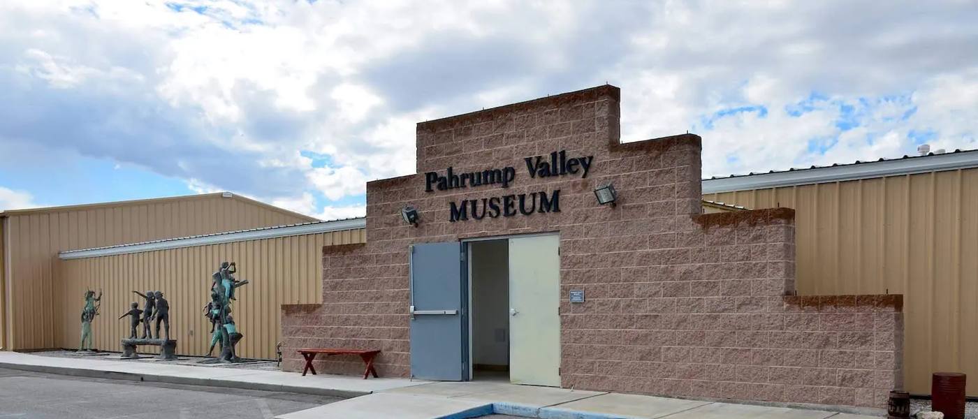 The museum entrance, a rough block facade with the doors standing open onto the parking lot.
