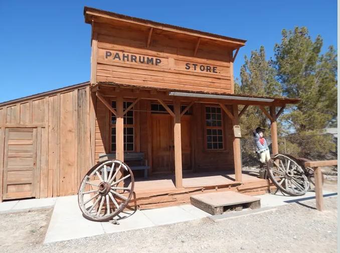 The false-fronted store building on the museum grounds with iron wagon wheels at the porch.