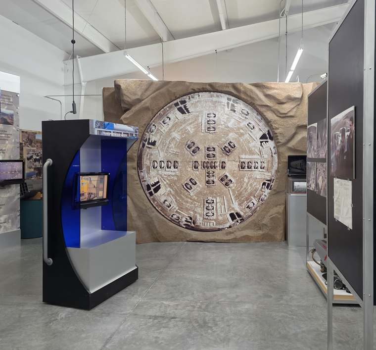 Gallery with a full-size image of a tunnel boring machine face set into a rock wall.